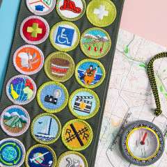 sash with scout badges next to a map and compass
